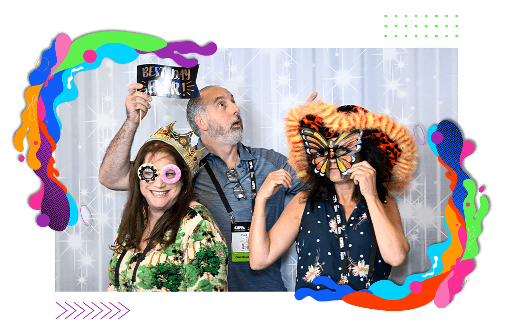Three people posed in a photo booth holding up fun props